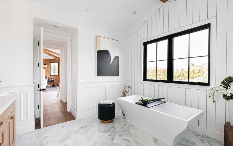Phòng tắm có bồn với tường ốp gỗ màu trắng, bố trí nội thất gọn gàng