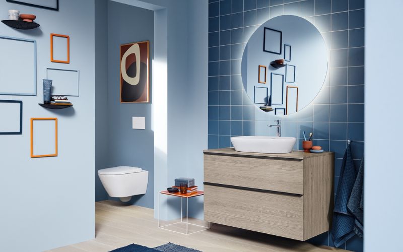 Nhà vệ sinh với gam màu xanh nhạt, bố trí kệ đính tường để đồ tiện ích 
