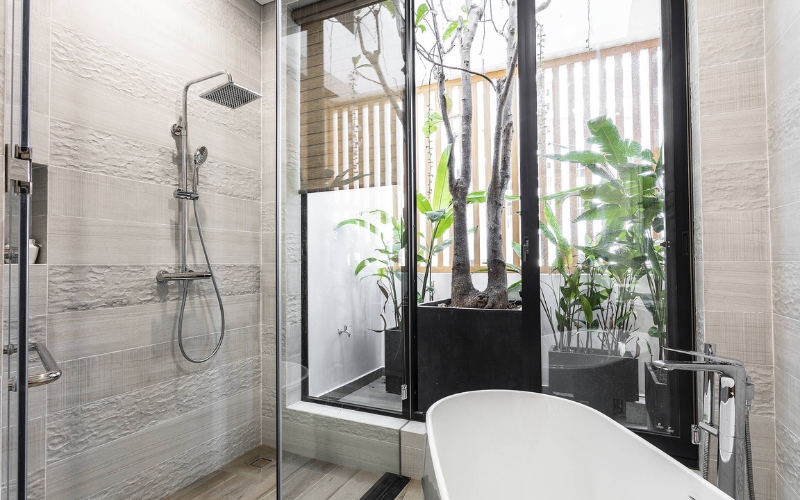 Nhà tắm thoáng đãng với cửa kính lớn cây xanh đặt góc gần gũi 